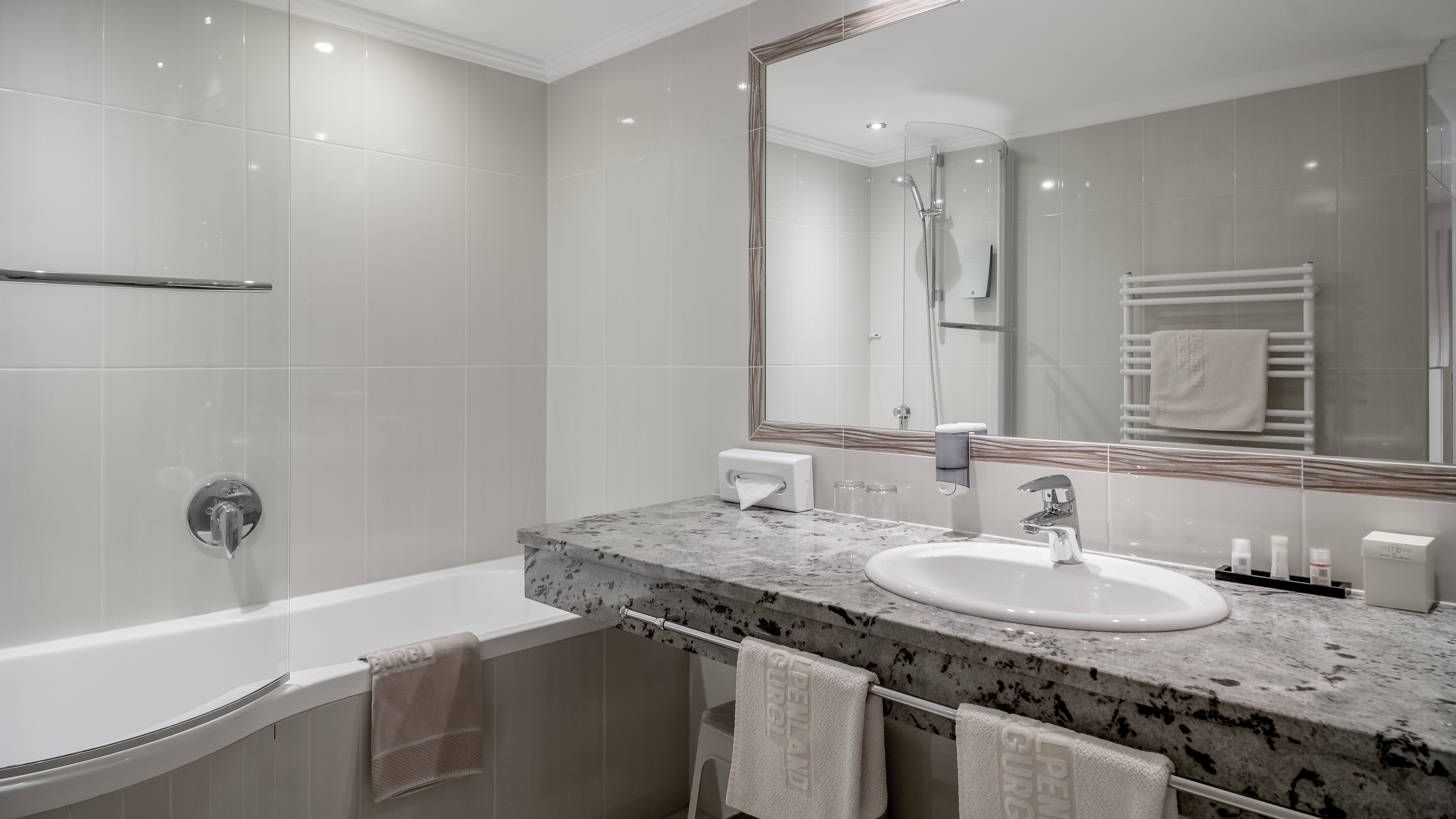 Elegantes modernes Badezimmer mit Luxuselementen Modernes Badezimmer mit Badewanne, Waschbecken und großem Spiegel, helle Fliesenwände und Accessoires.