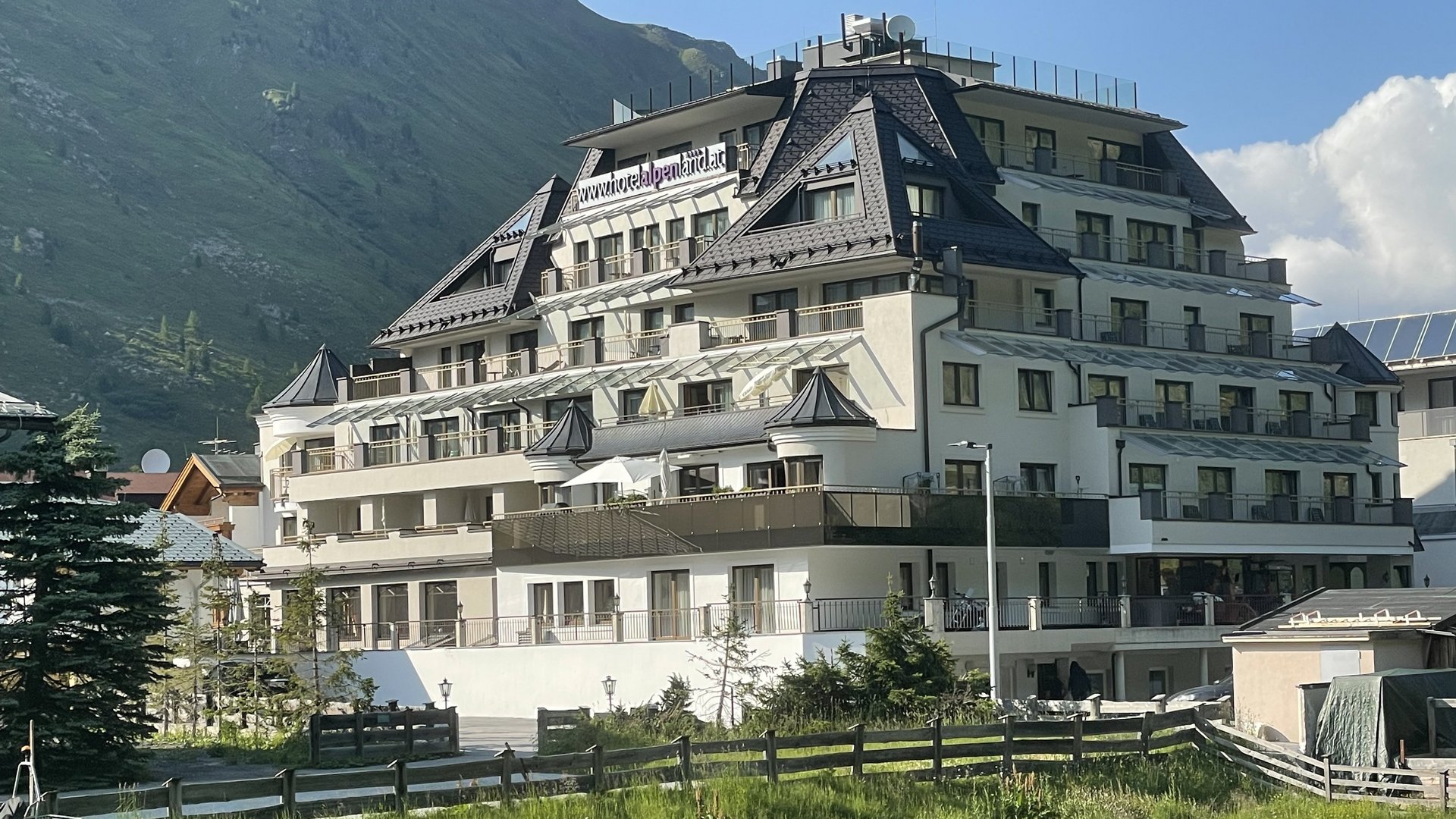 Mehrstöckiges Hotelgebäude in gebirgiger Umgebung mit umliegendem Grün und klarem Himmel