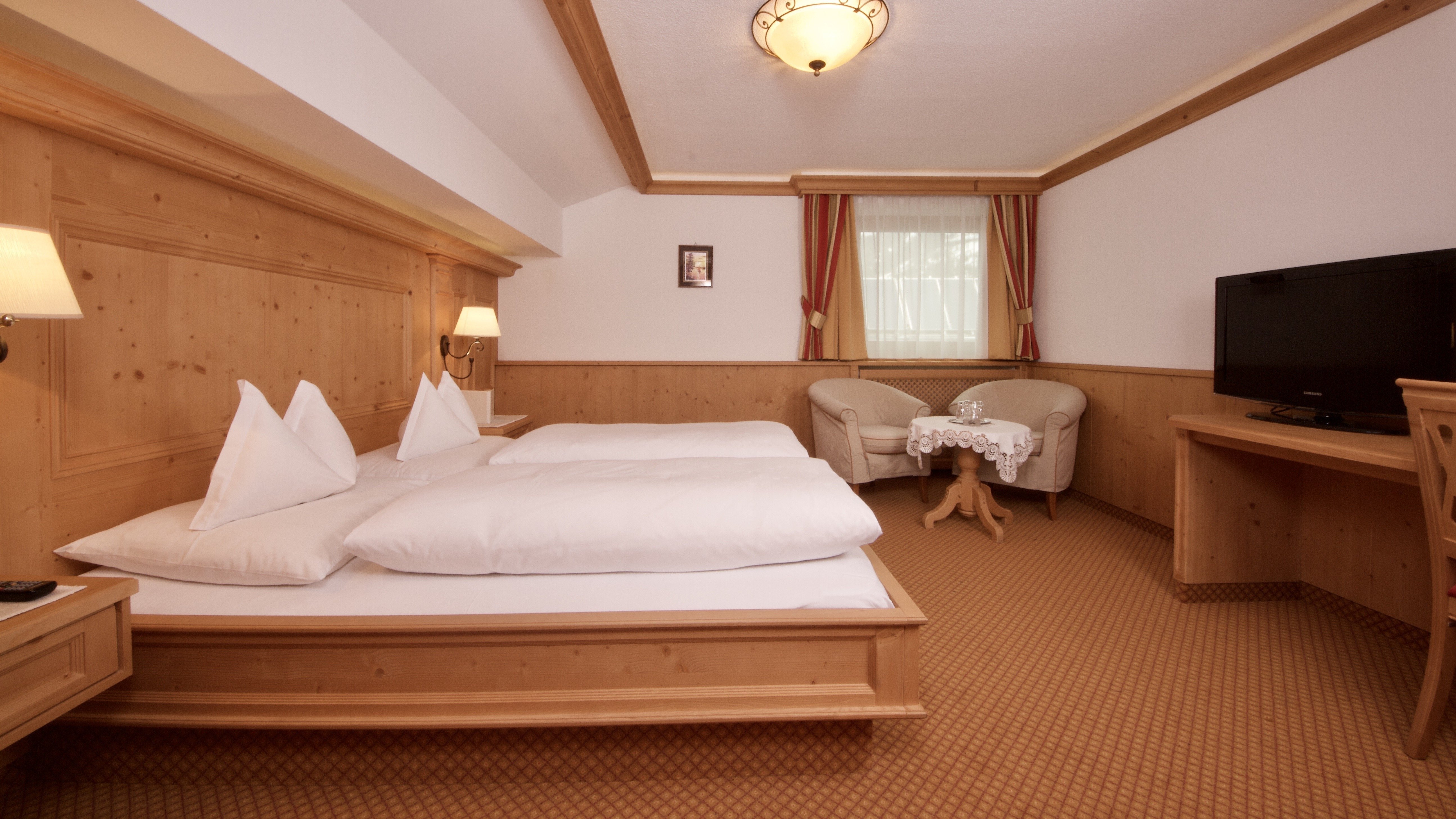 Gemütliches Zimmer mit Holzdesign Hotelzimmer mit zwei Betten, Sitzecke und Fernseher im Holzstil eingerichtet.