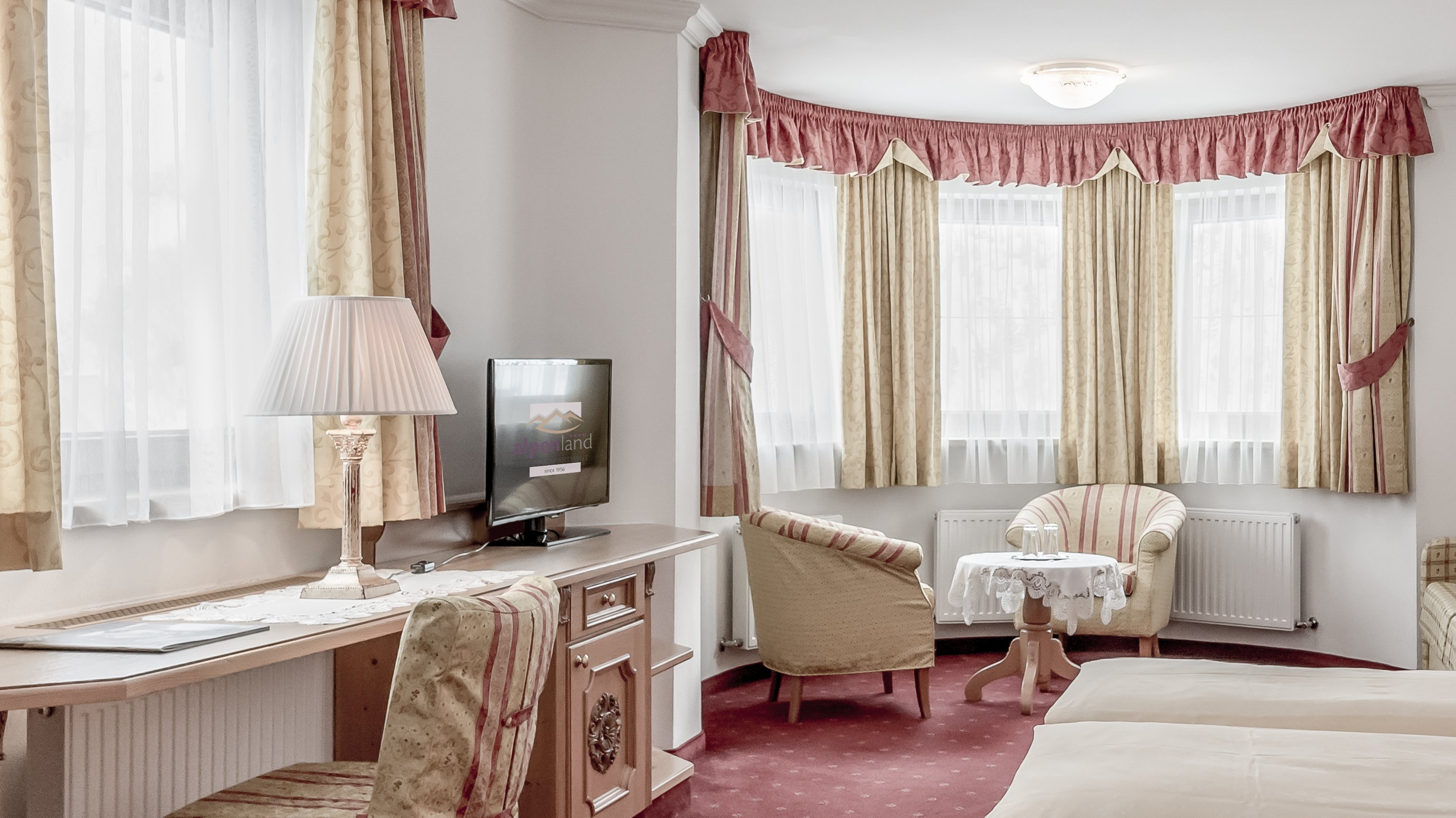 Elegante Hotelzimmergestaltung Helles Hotelzimmer mit großen Fenstern, einem kleinen Tisch und komfortablen Sitzgelegenheiten.