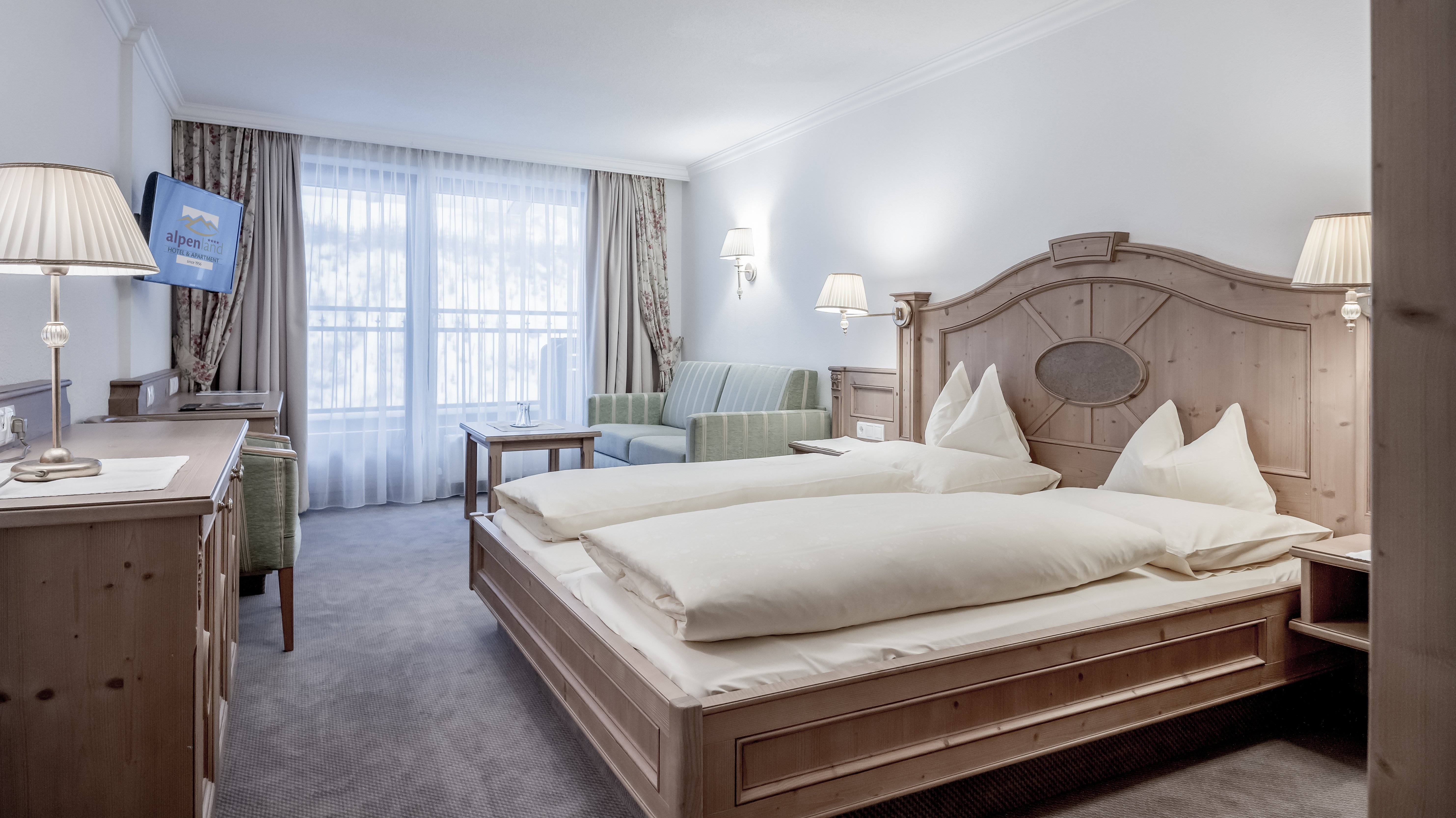 Luxuriöses Hotelzimmer im Alpenland Zwei Betten und ein Sitzbereich in einem gut gestalteten Hotelzimmer mit Tageslicht.