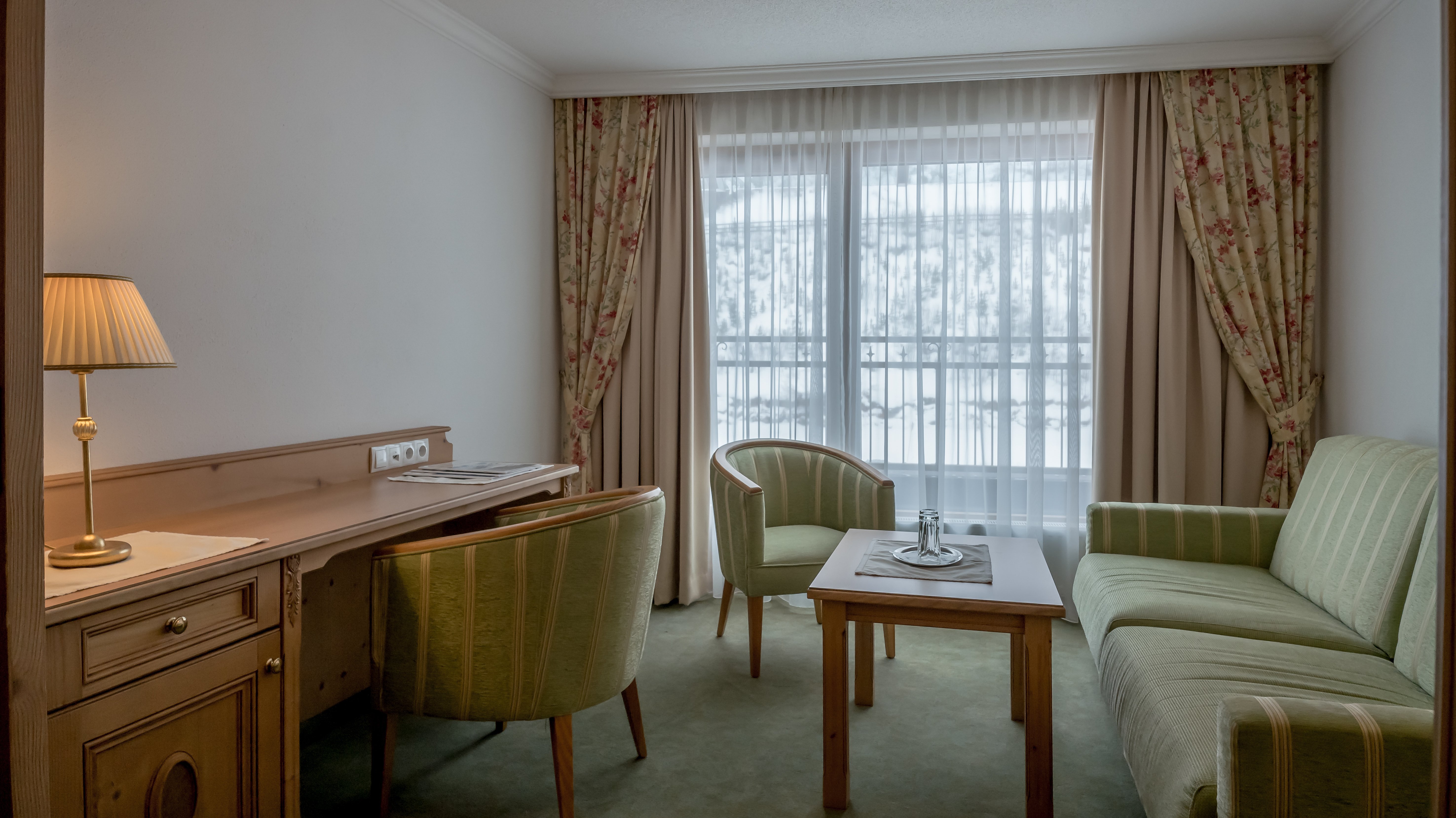 Helle Hotelzimmeransicht mit Tisch, zwei Stühlen und großen Fenstern für Aussicht.
