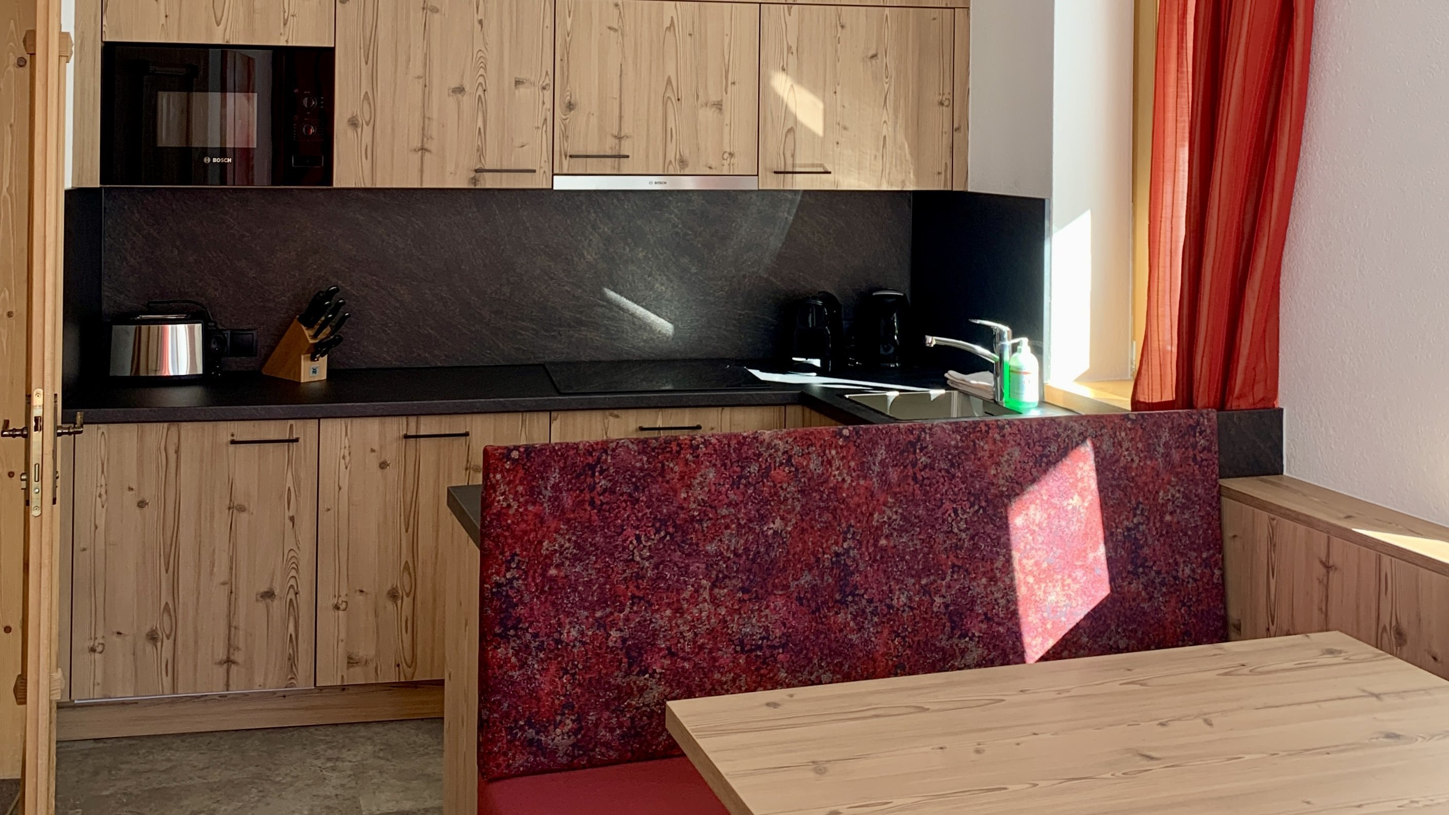 Moderne Küche mit Holzdetails Küche mit Holzschränken und Esstisch im modernen Design, Fenster mit roten Vorhängen.