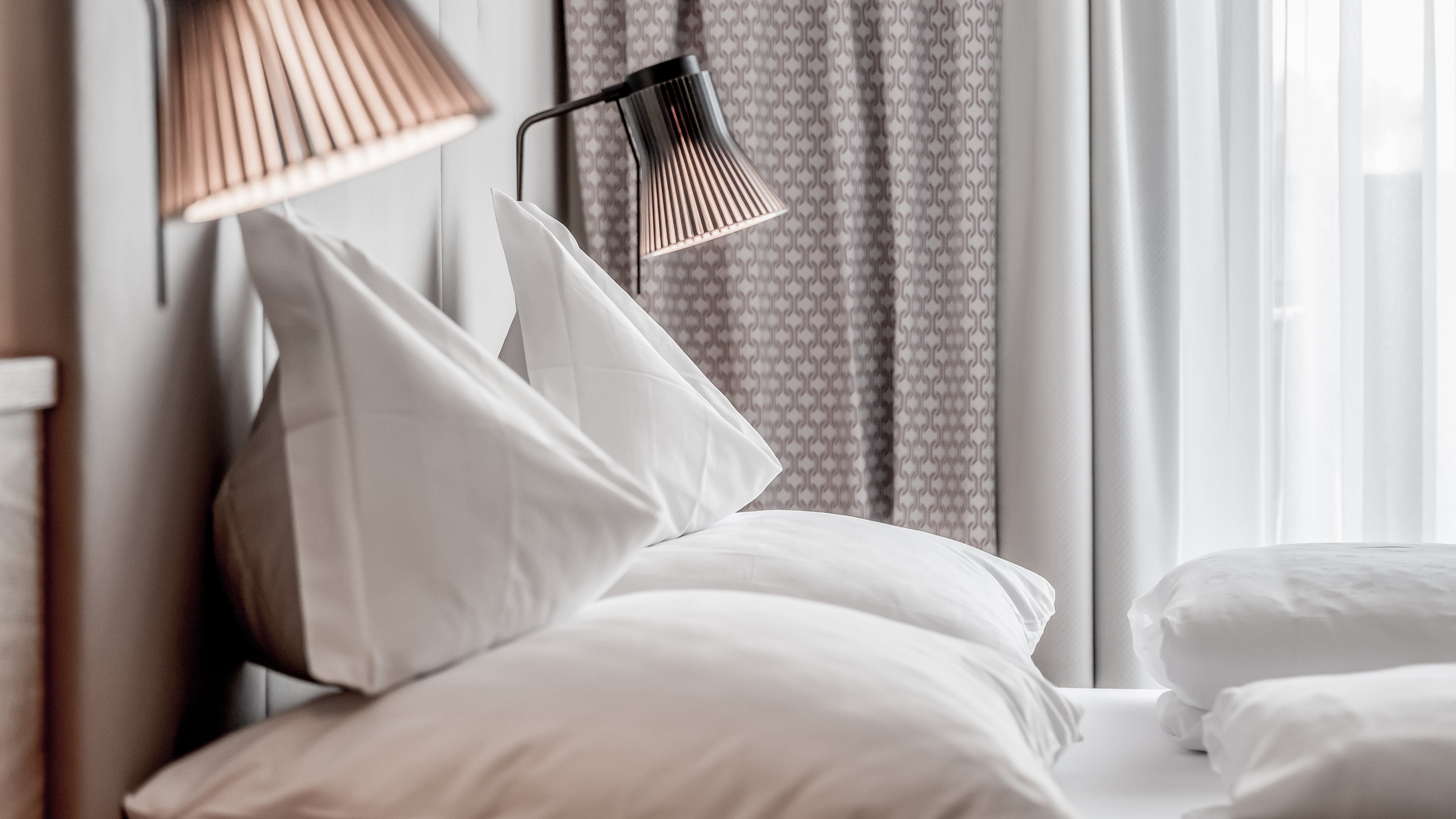 Moderne Hotelzimmer mit stilvollem Design Hotelzimmer mit zwei Kissen und modernen Lampen auf Nachttischen sichtbar. Schlichte, elegante Einrichtung.