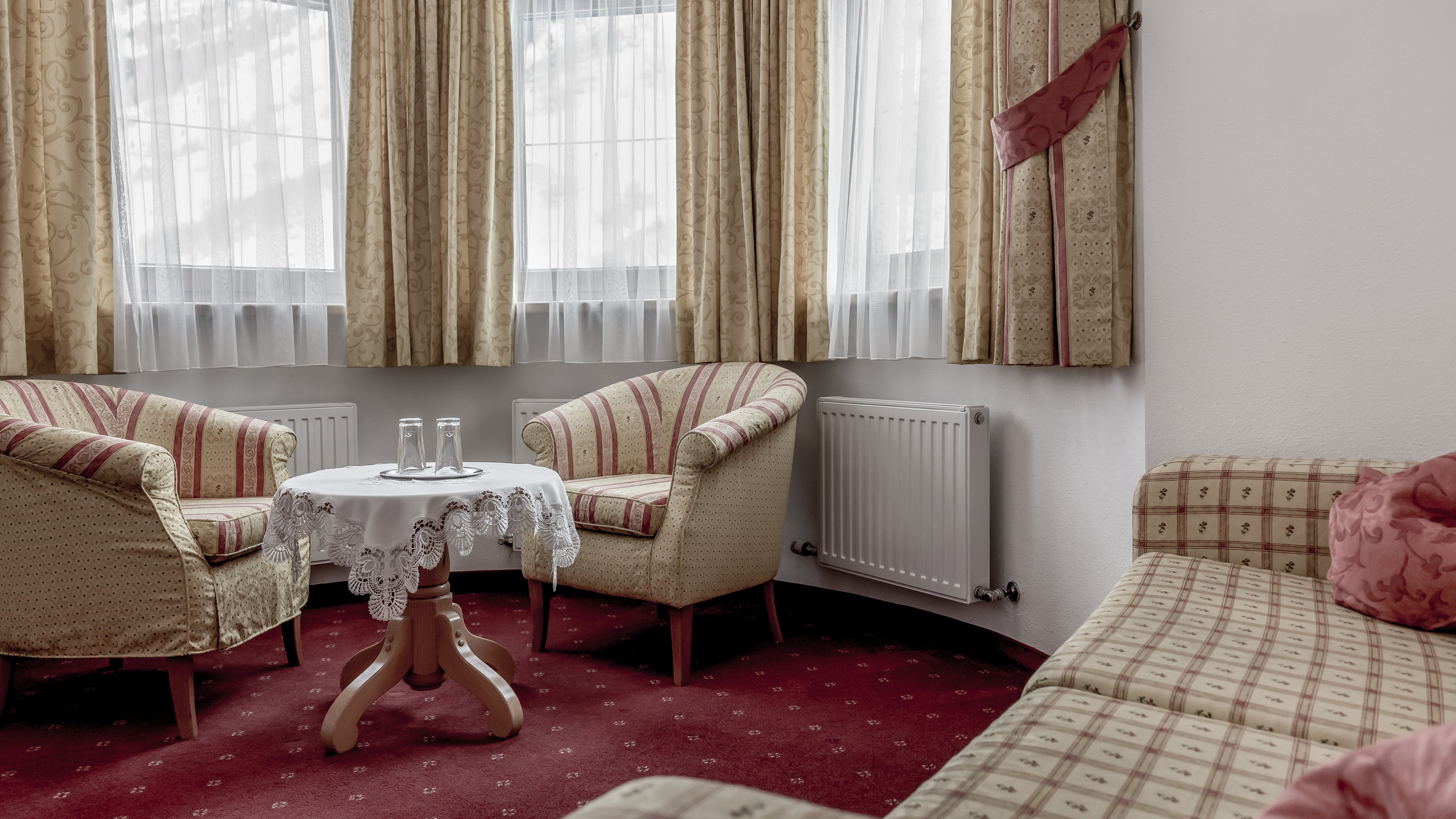 Gemütliche Wohnlandschaft im Alpenland Wohnzimmer mit zwei gemusterten Armstühlen, Tisch und Sofa um ein Fenster gruppiert.